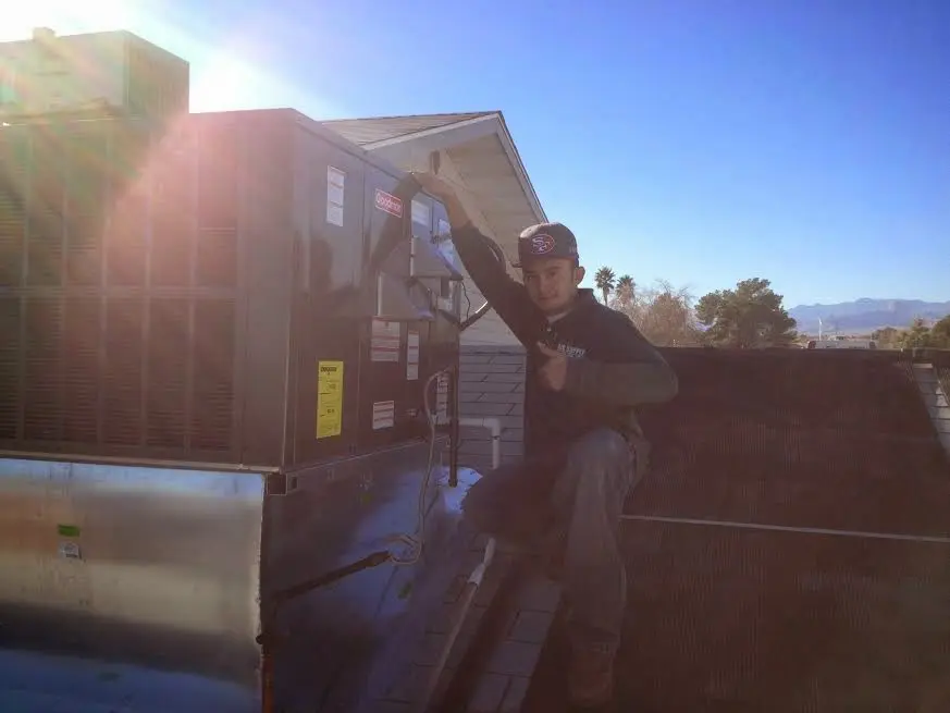 HVAC technician performing Air Duct Cleaning on a rooftop unit in Munhall